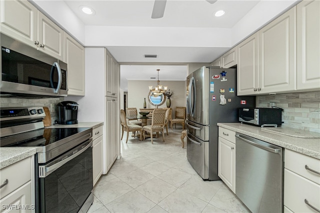 kitchen featuring appliances with stainless steel finishes, backsplash, a chandelier, white cabinetry, and hanging light fixtures