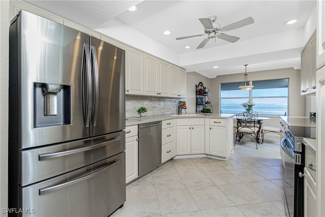 kitchen featuring backsplash, white cabinets, ceiling fan, decorative light fixtures, and stainless steel appliances