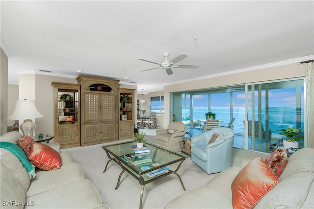 living room featuring ceiling fan, crown molding, a water view, and light colored carpet