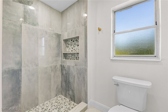 bathroom with a tile shower and toilet