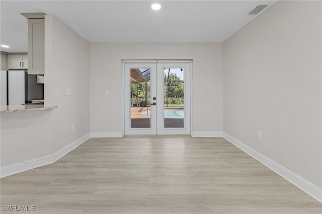 unfurnished room with french doors and light hardwood / wood-style flooring