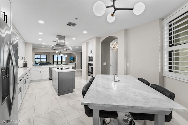 kitchen featuring white cabinetry, a center island, stainless steel appliances, kitchen peninsula, and island exhaust hood