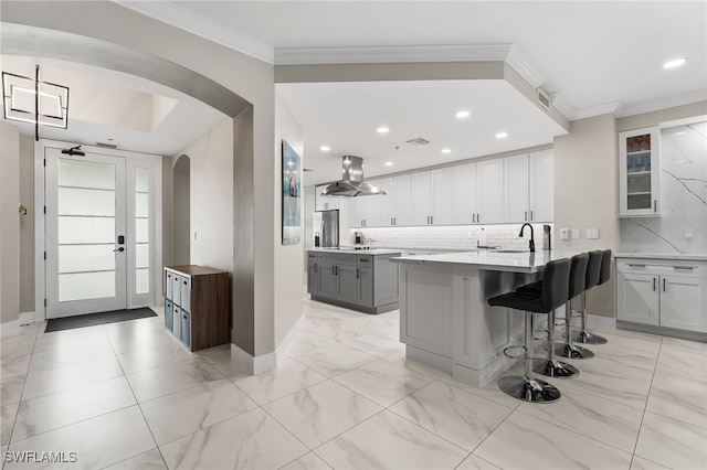 kitchen featuring stainless steel fridge with ice dispenser, backsplash, island exhaust hood, a breakfast bar area, and white cabinets