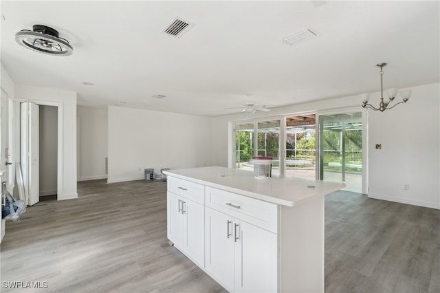 kitchen with pendant lighting, a center island, white cabinets, ceiling fan with notable chandelier, and light hardwood / wood-style floors