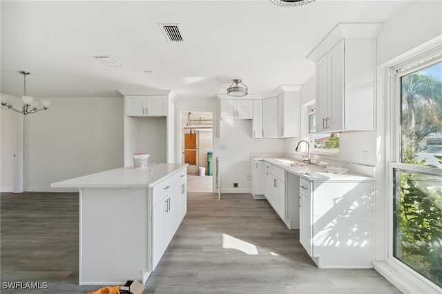 kitchen with light hardwood / wood-style floors, a center island, white cabinetry, and a wealth of natural light