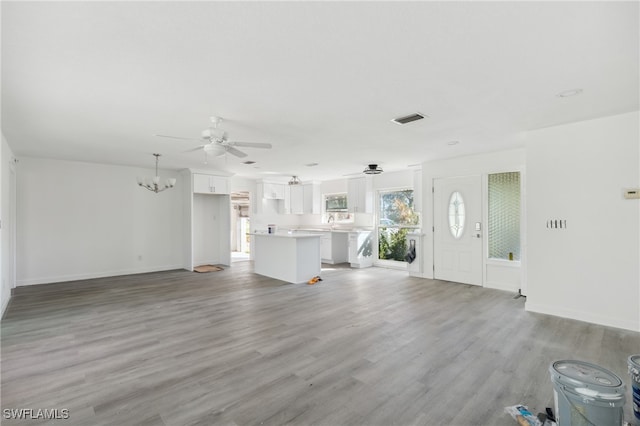 unfurnished living room featuring light hardwood / wood-style flooring and ceiling fan with notable chandelier