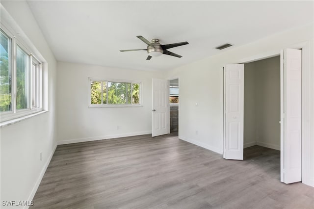 unfurnished bedroom featuring multiple windows, ceiling fan, and hardwood / wood-style floors