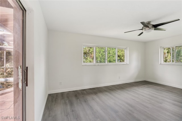 unfurnished room featuring ceiling fan, dark wood-type flooring, and a healthy amount of sunlight