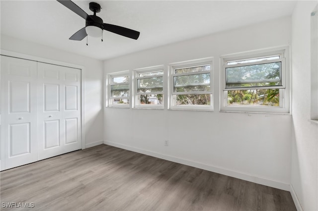 unfurnished bedroom featuring ceiling fan, a closet, and light wood-type flooring