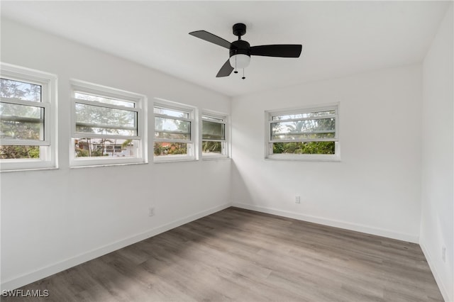 empty room with hardwood / wood-style flooring, ceiling fan, and a healthy amount of sunlight