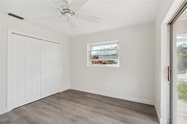 unfurnished bedroom featuring multiple windows, ceiling fan, and light wood-type flooring