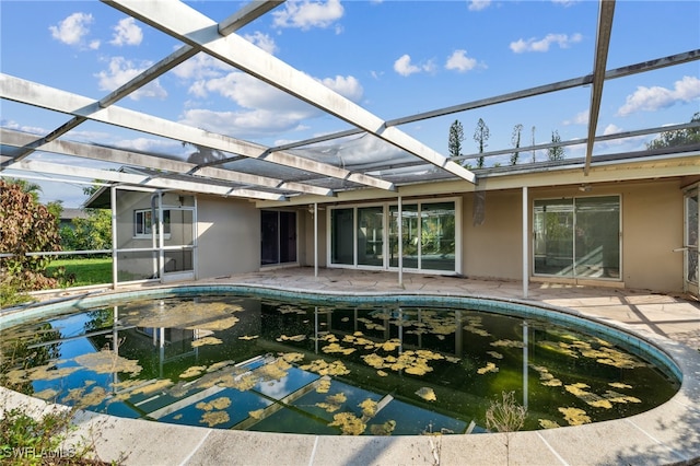 view of pool featuring glass enclosure and a patio area