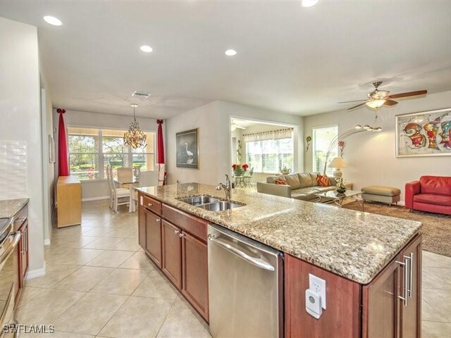 kitchen featuring stainless steel dishwasher, ceiling fan with notable chandelier, sink, pendant lighting, and a center island with sink