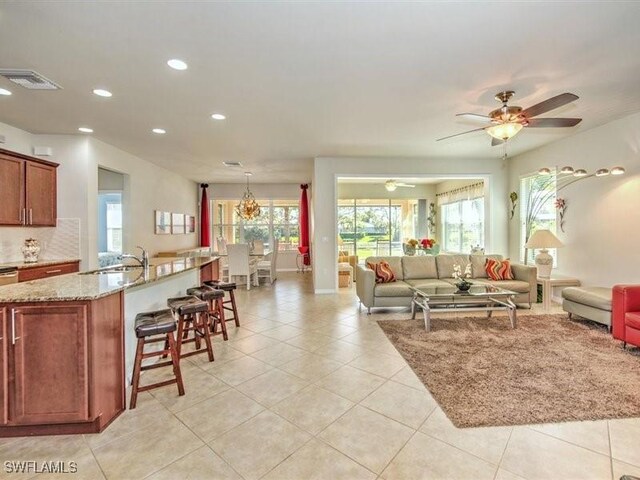 tiled living room with ceiling fan, plenty of natural light, and sink