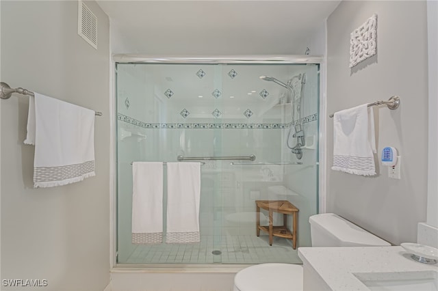 bathroom featuring a shower with shower door and toilet