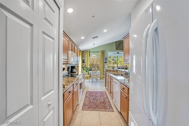 kitchen featuring appliances with stainless steel finishes, pendant lighting, light tile patterned floors, stone countertops, and lofted ceiling