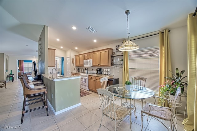 kitchen featuring light stone countertops, kitchen peninsula, vaulted ceiling, white appliances, and light tile patterned floors