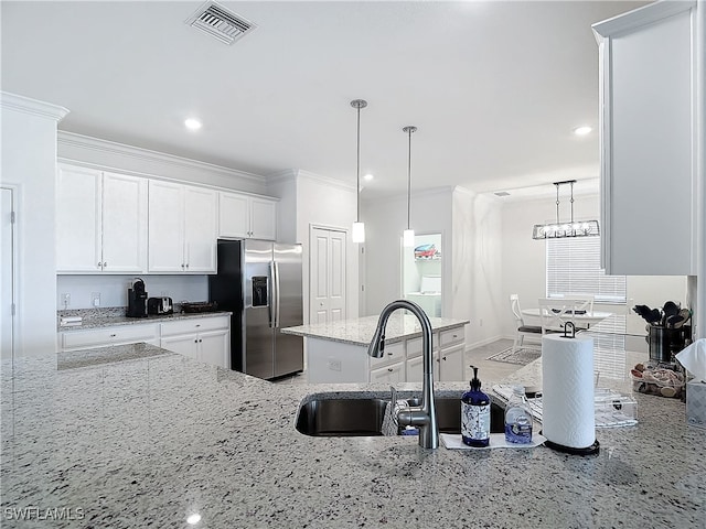 kitchen with stainless steel refrigerator with ice dispenser, pendant lighting, white cabinetry, and crown molding