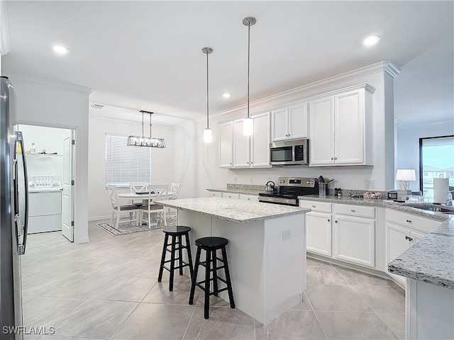 kitchen with a kitchen island, white cabinetry, stainless steel appliances, and hanging light fixtures