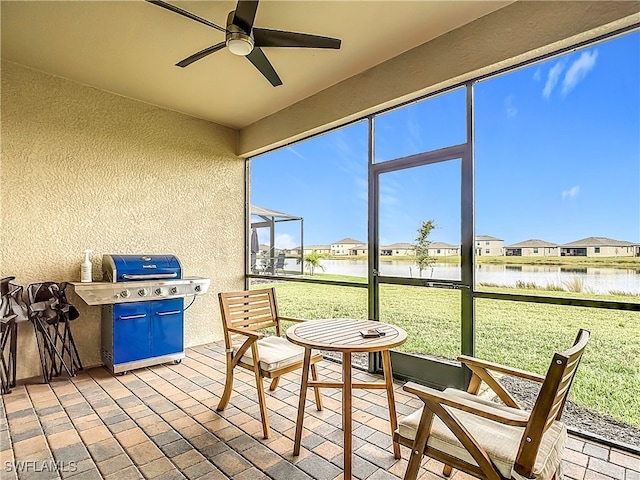 sunroom / solarium featuring ceiling fan and a water view