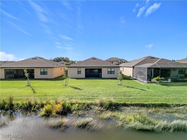 rear view of house with a lanai, a yard, and a water view