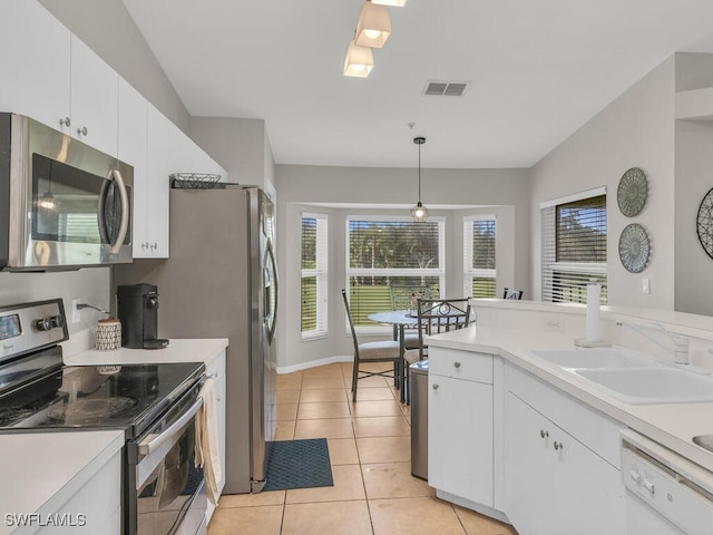 kitchen with white cabinets, hanging light fixtures, appliances with stainless steel finishes, and vaulted ceiling