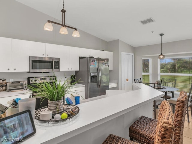 kitchen with pendant lighting, white cabinets, lofted ceiling, and appliances with stainless steel finishes