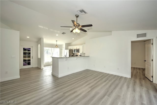 unfurnished living room with light wood-type flooring, vaulted ceiling, and ceiling fan