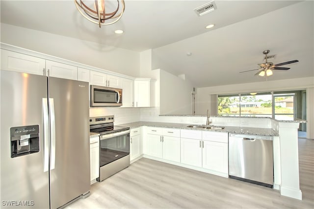 kitchen featuring vaulted ceiling, stainless steel appliances, white cabinetry, and sink