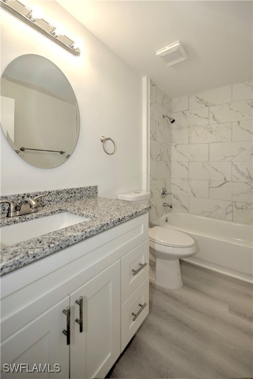 full bathroom featuring toilet, vanity, tiled shower / bath combo, and hardwood / wood-style flooring