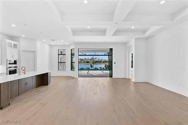 unfurnished living room with beamed ceiling, light hardwood / wood-style flooring, coffered ceiling, and sink