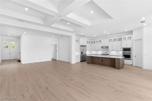 kitchen with light wood-type flooring, built in appliances, white cabinetry, and a large island