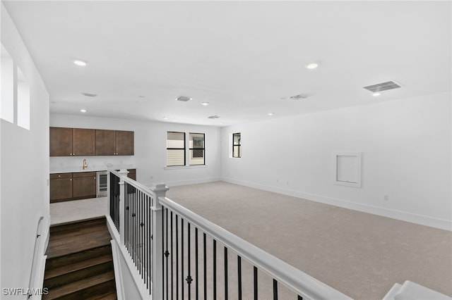 corridor with wine cooler, sink, and dark carpet