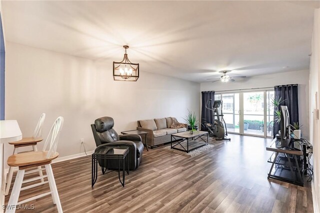 living room featuring ceiling fan with notable chandelier and hardwood / wood-style flooring