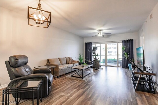 living room with ceiling fan with notable chandelier and wood-type flooring