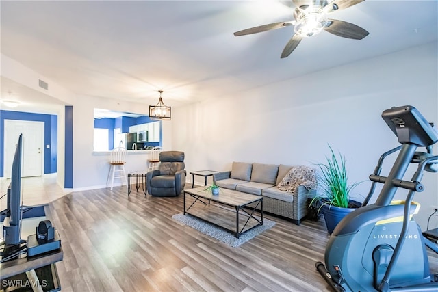 living room featuring wood-type flooring and ceiling fan with notable chandelier