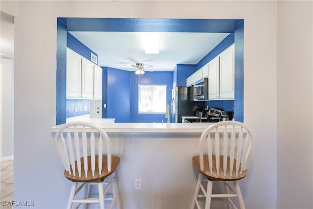 kitchen with white cabinets, ceiling fan, a kitchen bar, and appliances with stainless steel finishes