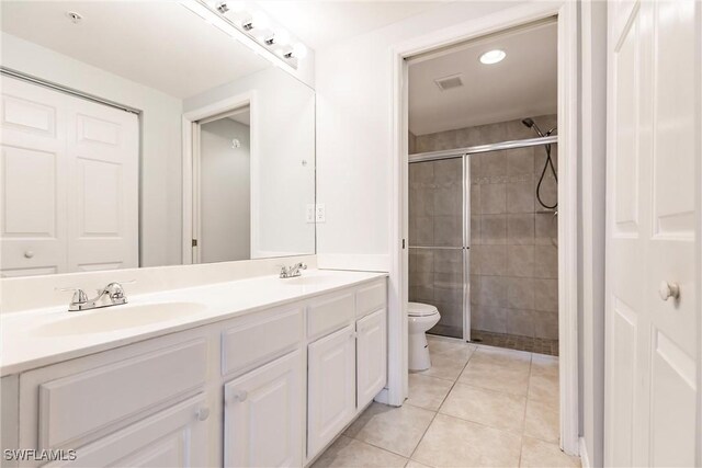 bathroom featuring tile patterned flooring, vanity, toilet, and walk in shower