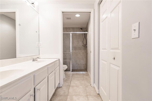 bathroom with tile patterned flooring, vanity, toilet, and a shower with shower door