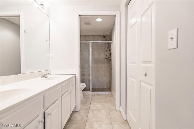 bathroom featuring double vanity, toilet, a stall shower, a sink, and tile patterned flooring