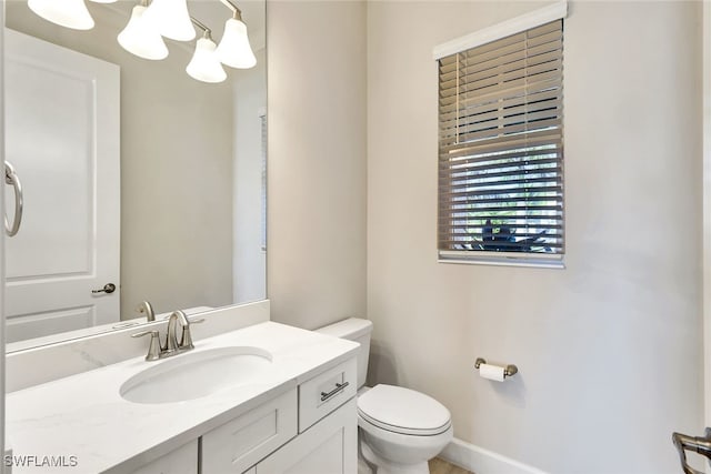 bathroom featuring toilet, vanity, and a notable chandelier