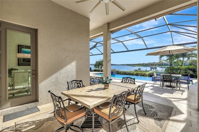 view of patio / terrace with a lanai, a water view, and ceiling fan