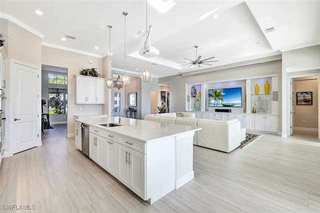 kitchen with sink, decorative light fixtures, white cabinets, an island with sink, and a raised ceiling