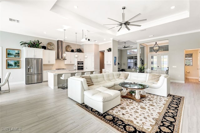 living room with a tray ceiling, ceiling fan, french doors, and crown molding