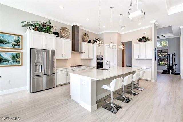 kitchen with white cabinetry, an island with sink, wall chimney range hood, and appliances with stainless steel finishes