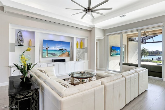 living room featuring a raised ceiling, ceiling fan, and ornamental molding