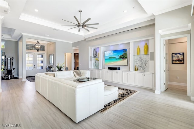 living room featuring a tray ceiling, light hardwood / wood-style floors, crown molding, ceiling fan, and french doors