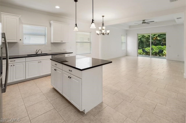 kitchen with white cabinetry, sink, a center island, pendant lighting, and ceiling fan with notable chandelier