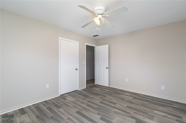 empty room with ceiling fan and dark hardwood / wood-style flooring