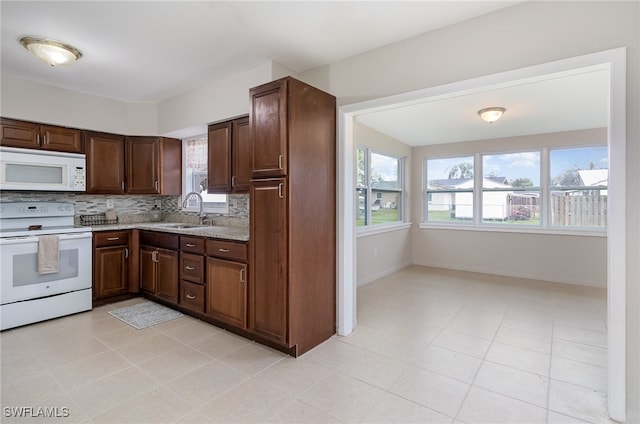 kitchen with tasteful backsplash, dark brown cabinets, white appliances, sink, and light tile patterned floors